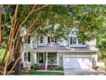 Charming two-story home with a welcoming front porch, lush greenery, and a two-car garage at 115 E Seve Ct, Morrisville, NC 27560