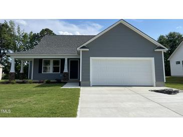 Charming one-story home featuring a two-car garage, and a well-manicured lawn at 140 Oakfield Trace Dr, Four Oaks, NC 27524