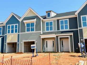 Modern townhome exterior featuring varied siding colors, large windows, and attached garages, offering contemporary living at 99 Ripple Way # 211, Clayton, NC 27520