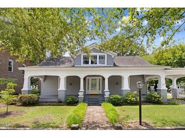 Charming gray home featuring a covered front porch, manicured landscaping, and a walkway leading to the inviting entrance at 125 W Pine St, Pine Level, NC 27568