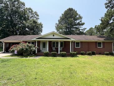 Charming brick ranch with a covered front porch, complemented by mature trees and a well-manicured lawn at 2433 Zacks Mill Rd, Angier, NC 27501