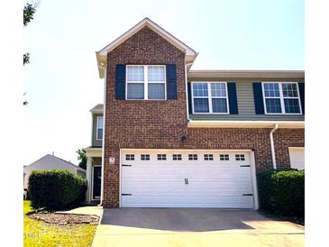 Two-story townhouse with brick facade, a two-car garage, dark shutters, and manicured landscaping at 2452 Bay Harbor Dr, Raleigh, NC 27604