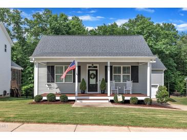 Charming home featuring a welcoming front porch, American flag, and beautifully landscaped lawn at 267 Ashley Woods Ct, Clayton, NC 27527