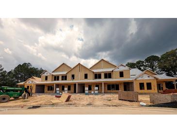 New construction of townhomes with wood framing and dark storm clouds above at 2930 Alyssa Ct, Knightdale, NC 27604