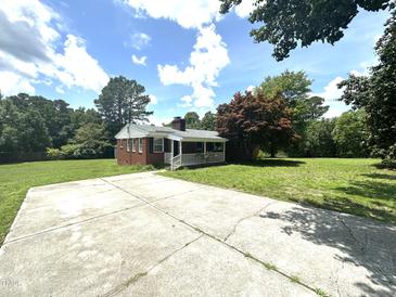 Charming brick home with front porch, spacious yard, and ample parking on a sunny day at 4796 Covered Bridge Rd, Archer Lodge, NC 27527