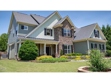 Charming home with a stone facade, well-manicured lawn and beautiful landscaping at 604 Nottely Pl, Cary, NC 27519