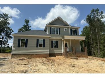 Two-story home featuring gray siding, black shutters, and a charming front porch with brick accents, and beautiful, ample windows at 80 Copper Penny Rd, Zebulon, NC 27597