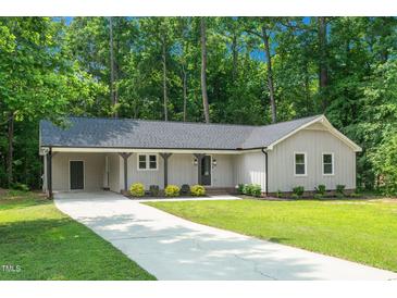 Charming home with a well-manicured lawn, a grey roof and siding, and a side carport at 1308 Broken Branch Ct, Raleigh, NC 27610