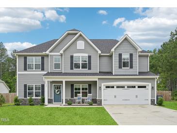 Charming two-story home featuring a well-manicured lawn, two-car garage, and inviting front porch with rocking chairs at 195 Solomon Dr, Cameron, NC 28326