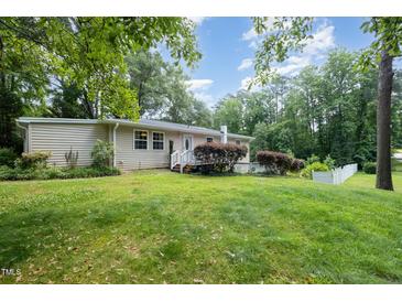 A spacious backyard featuring lush green grass and mature trees creates a private outdoor oasis at 3012 Optimist Farm Rd, Apex, NC 27539