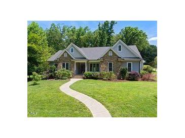 Charming single-story home with stone accents and a well-manicured lawn and paved walkway at 311 Rassie Crabtree Rd, Rougemont, NC 27572