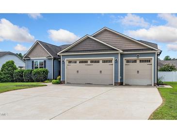 Spacious three-car garage with a concrete driveway and an attached blue-gray home at 45 Imperial Dr, Clayton, NC 27527