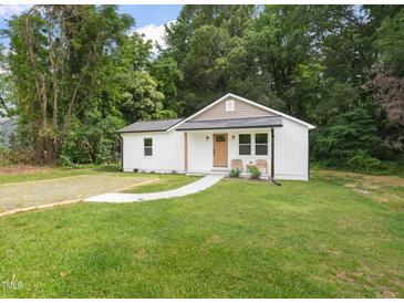 Charming renovated cottage with a manicured lawn, inviting walkway and rocking chair front porch at 1621 N Park Ave, Burlington, NC 27217