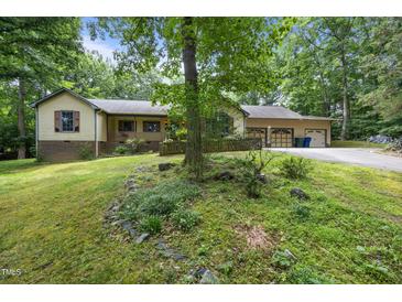 Charming home exterior featuring a lush lawn, mature trees, and a welcoming two-car garage at 2382 Council Rd, Graham, NC 27253