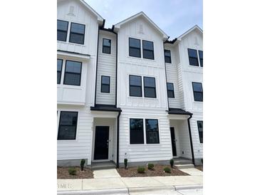 Modern townhome with a white exterior, black window frames, and a well-manicured front yard at 3103 White Blossom Ct, Raleigh, NC 27610