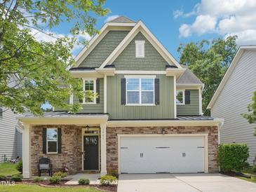 Two-story home with green siding, stone accents, and a two-car garage on a sunny day at 3901 Yates Mill Trl, Raleigh, NC 27606