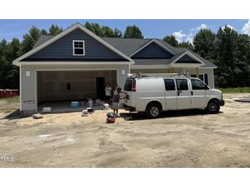 New construction home featuring a gray facade, open garage, and a work van in the driveway at 4024 N Nc 581 Hwy, Kenly, NC 27542
