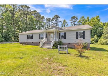 Inviting home featuring a well-maintained lawn, charming front porch, and gray siding at 589 Atkinson Mill Rd, Selma, NC 27576