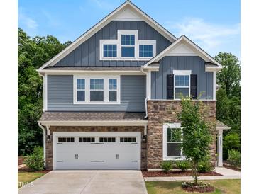 Beautiful two-story home featuring stone accents, a two-car garage, and professionally landscaped front yard at 7117 Crested Iris Pl, Durham, NC 27703