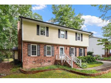 Charming two-story home featuring a brick facade, light yellow siding, black shutters and a well-manicured lawn at 7209 St Ledger Dr, Raleigh, NC 27613