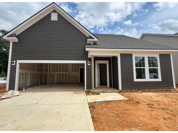 New construction home showcasing a two-car garage and stylish gray siding under a cloudy sky at 798 Old Station Pointe, Angier, NC 27501
