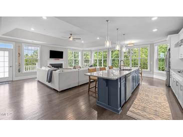 Open-concept living room flows into kitchen, boasting hardwood floors, fireplace, and abundant natural light at 10310 Sablewood Dr # 211, Raleigh, NC 27617