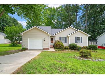 Charming single-story home with a well-maintained lawn, lush landscaping, and an attached garage at 1409 Beckworth Ct, Garner, NC 27529