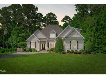 Charming single-story home featuring a lush green lawn, mature trees, and a welcoming front entrance at 3104 Whitehart Ln, Apex, NC 27539