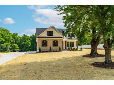 Charming two-story home featuring brick and siding, complemented by a well-manicured lawn and mature trees at 4924 Zebulon Rd, Zebulon, NC 27597