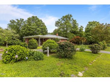 Charming brick ranch home featuring mature landscaping and a well-maintained front yard at 5918 Efland Cedar Grove Rd, Cedar Grove, NC 27231