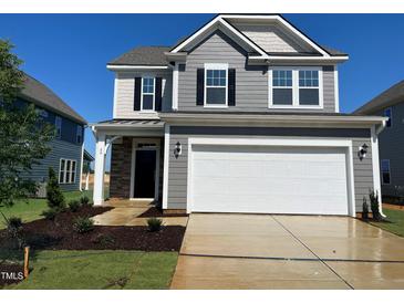 Two-story home featuring gray siding, stone accents, two-car garage, and well-manicured lawn at 88 Willow Cameron Way, Angier, NC 27501
