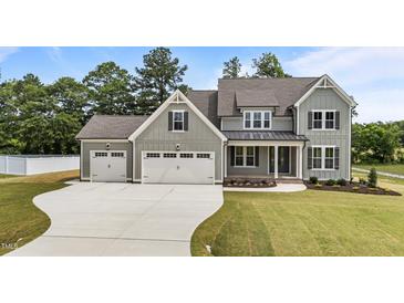 Charming two-story home featuring a three-car garage, landscaped yard, and covered front porch at 90 Lane Farms Way Way, Holly Springs, NC 27540