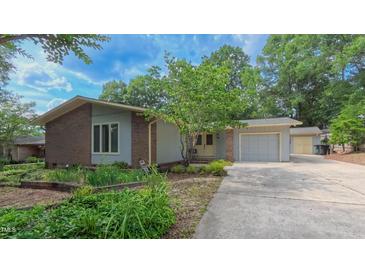 Charming exterior elevation features a brick facade, attached garage, and mature landscaping at 1815 Hawthorne Ln, Burlington, NC 27215
