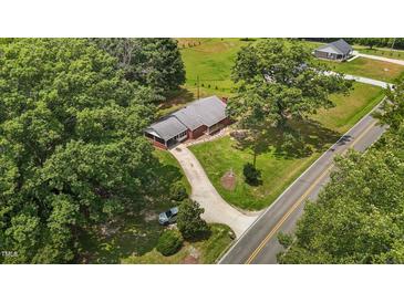 An aerial view of a single-story brick home with a long driveway and mature trees, complemented by a lush green lawn at 2291 Gentry Ridge Rd, Roxboro, NC 27574