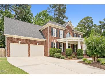 Traditional brick home with a two-car garage, manicured landscaping, and a welcoming front porch with white pillars at 325 Wescott Ridge Dr, Holly Springs, NC 27540