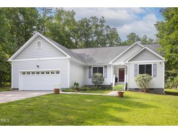 Charming home with a manicured lawn, attached garage, and inviting curb appeal under a partly cloudy sky at 404 Denton St, Durham, NC 27713