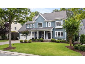 Beautiful two-story home with a blue exterior, lush lawn, and a two-car garage, complemented by mature trees and landscaping at 404 Wanderview Ln, Holly Springs, NC 27540