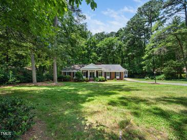 Ranch-style home with lush green lawn and mature trees at 4909 Brookhaven Dr, Raleigh, NC 27612