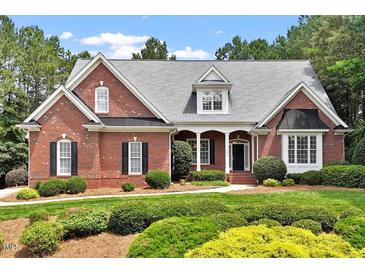 Charming brick home with a manicured lawn, lush landscaping, and covered front porch at 122 Barringer Dr, Garner, NC 27529