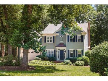Charming two-story home with blue shutters, brick chimney, mature trees, and a well-manicured lawn at 5109 Windance Pl, Holly Springs, NC 27540