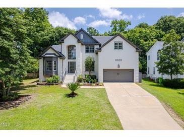 Charming two-story home with landscaped yard, a two-car garage, and beautiful architectural details at 8828 Deerland Grove Dr, Raleigh, NC 27615