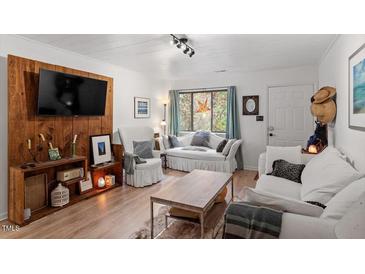 Cozy living room with a wood accent wall and comfortable white sofas offers a relaxing space at 1009 Iredell St # D, Durham, NC 27705