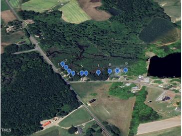 Aerial view showcasing available lots amid lush greenery and a tranquil pond setting at 12600 Old Stage Rd, Willow Springs, NC 27592