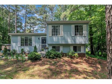 Charming split-level home featuring light blue siding, white shutters and a beautifully landscaped front yard at 320 Bainbridge Cir, Garner, NC 27529