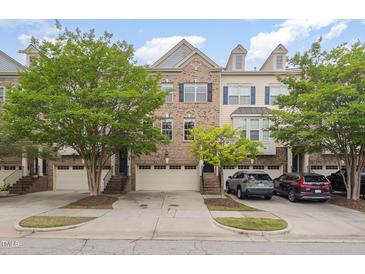 Charming townhome exterior featuring a brick facade, attached garages, and well-maintained landscaping at 404 Panorama Park Pl, Cary, NC 27519