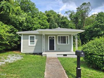 Charming single-story home features a welcoming front porch, complemented by a lush green lawn and mature trees at 511 Commonwealth St, Durham, NC 27703