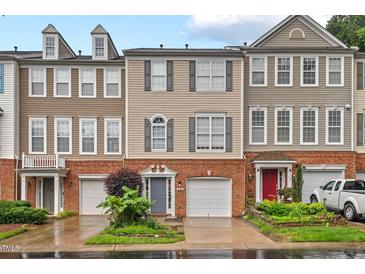 Charming townhome with brick and beige siding, complemented by a well-manicured front yard and attached garages at 5505 Heather Garden Way, Raleigh, NC 27613