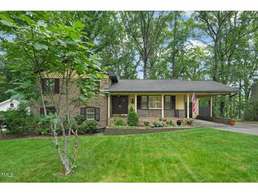 Charming brick home with a well-manicured lawn, mature trees, and inviting curb appeal at 5523 Newberry Dr, Raleigh, NC 27609