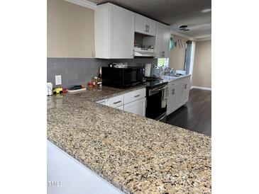 Modern kitchen featuring granite countertops, stainless steel appliances, and white cabinetry at 57 Winding Ridge Rdg, Sanford, NC 27332