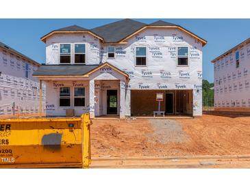 New construction home featuring a two-car garage and covered porch, with Tyvek wrap and construction materials surrounding at 756 Deschutes Dr, Garner, NC 27529